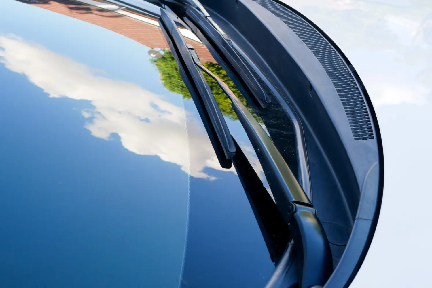 Close up of a car's windshield that is so clean the sky and clouds are perfectly reflected in it.